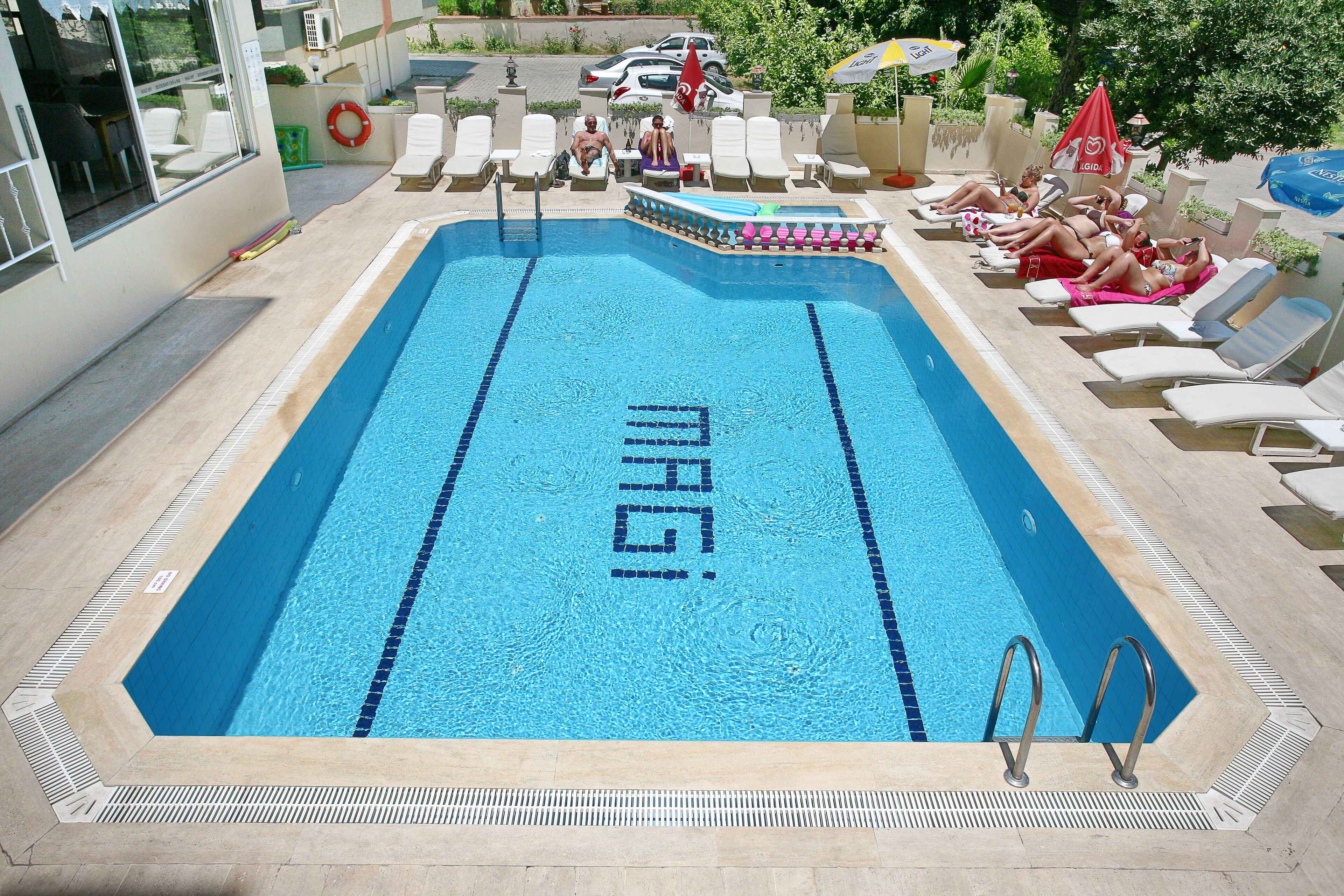 A swimming pool with 'MAGI' written in the center, surrounded by lounge chairs and a poolside area.