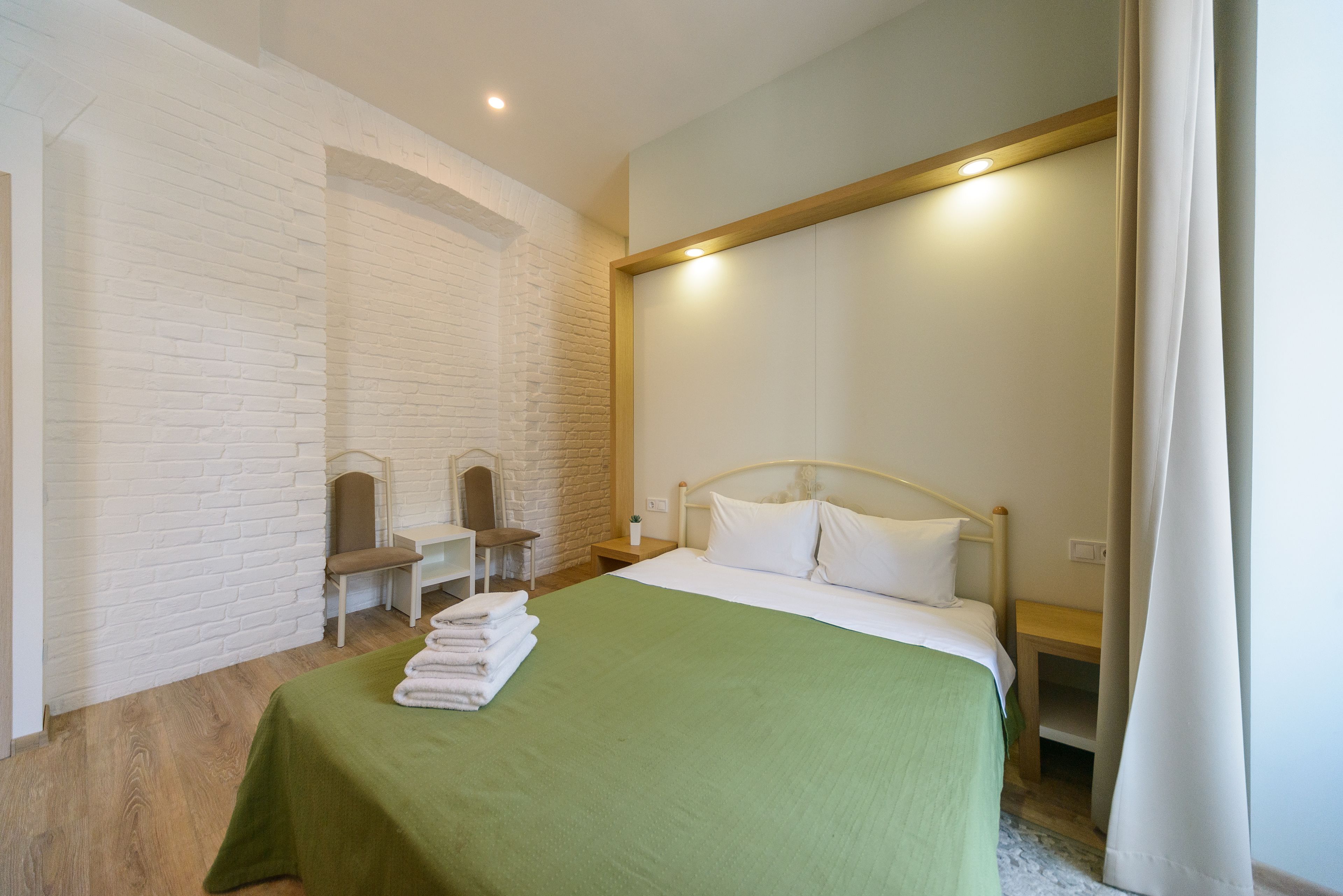 Een hotelkamer met een bed, een bankje, een stoel en een kleine tafel.