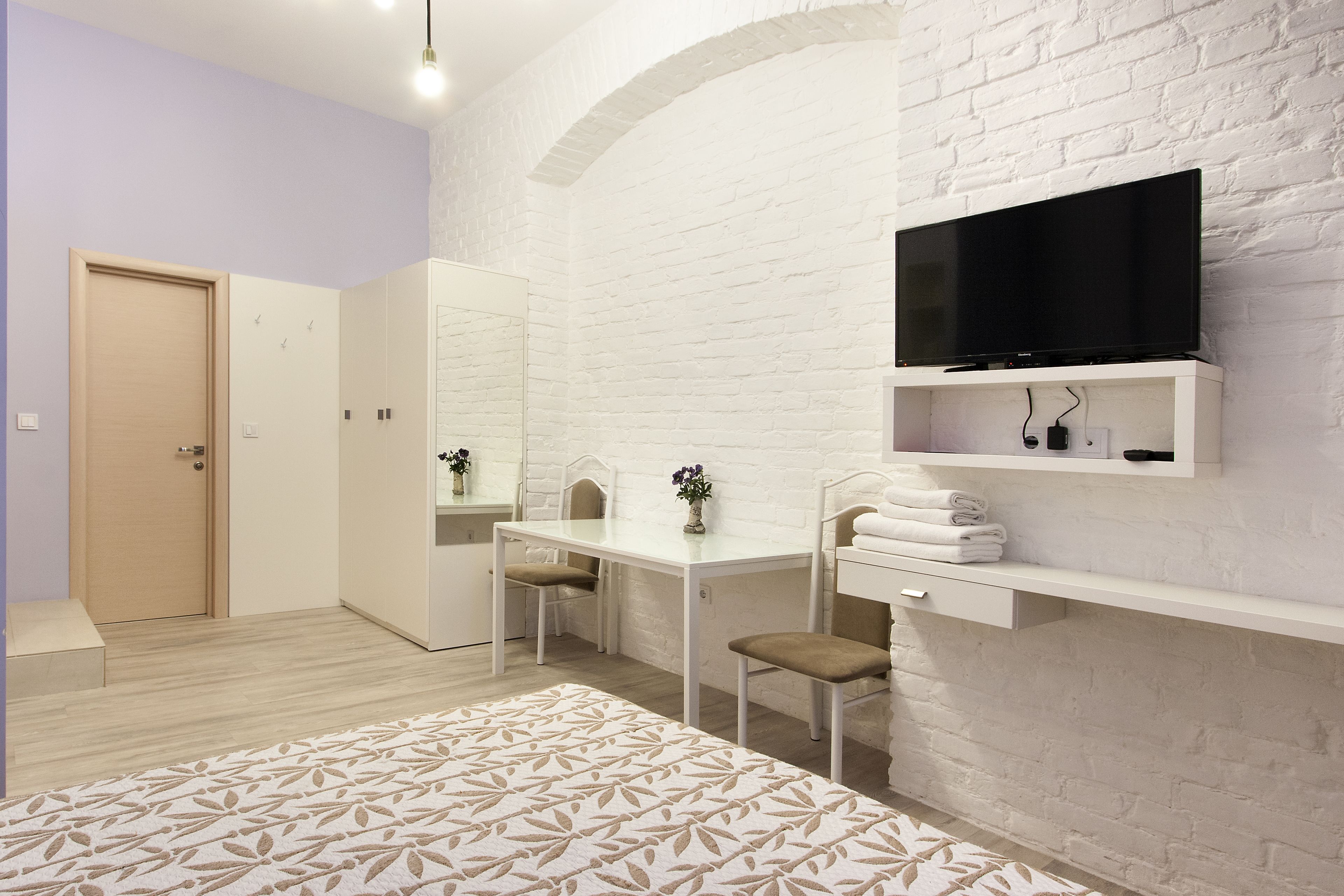 Un dormitorio moderno con una cama, un escritorio, una silla, un televisor y un armario.