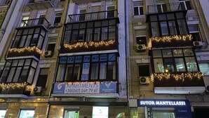 A multi-story building with balconies, a sign for 'Apartments' with contact information, and a storefront for 'Sutor Mantellassi' with a sign indicating 'Luxury Italian shoes'. - Centrooms (Kyiv)