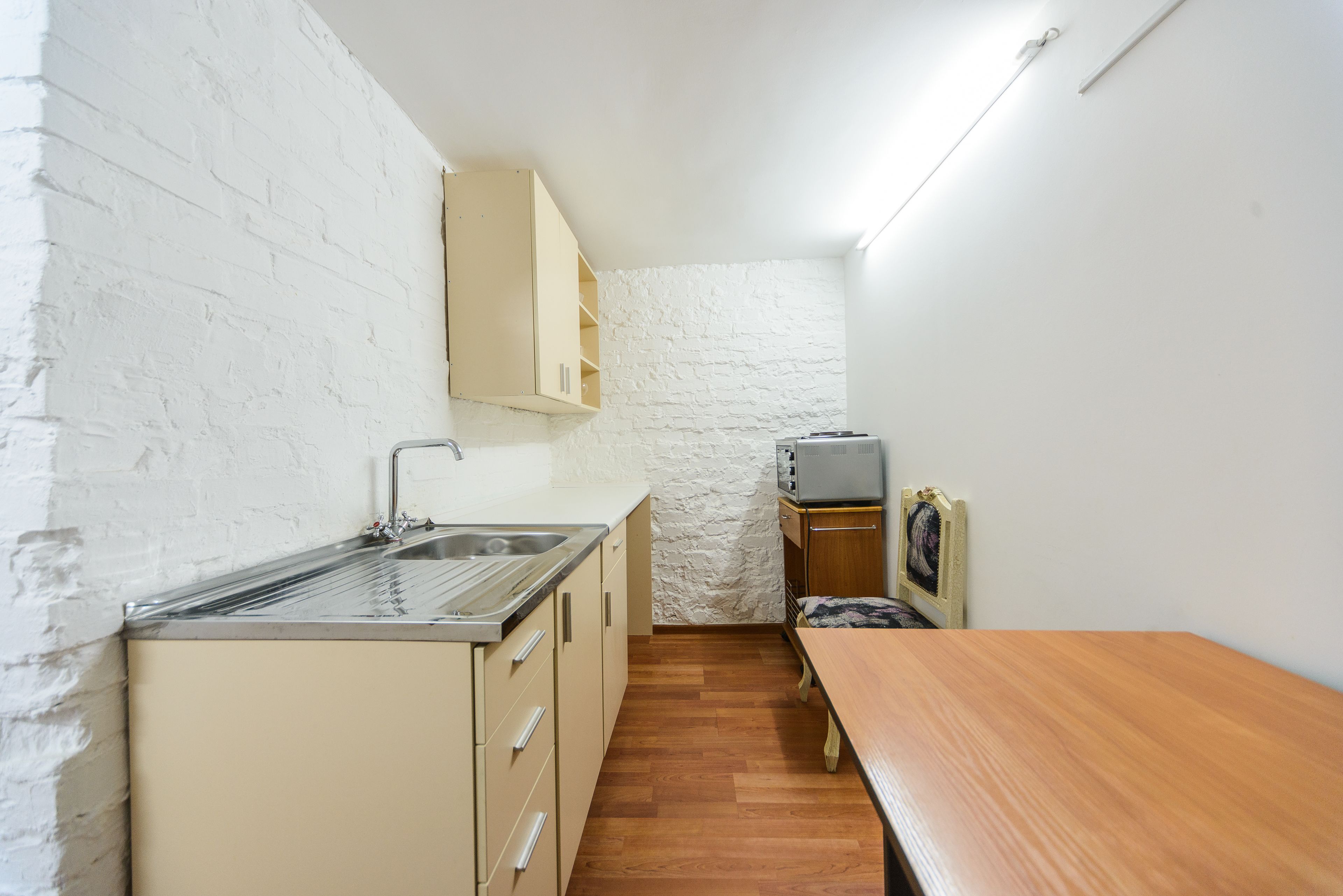 A compact kitchen with a sink, cabinets, and a wooden table.