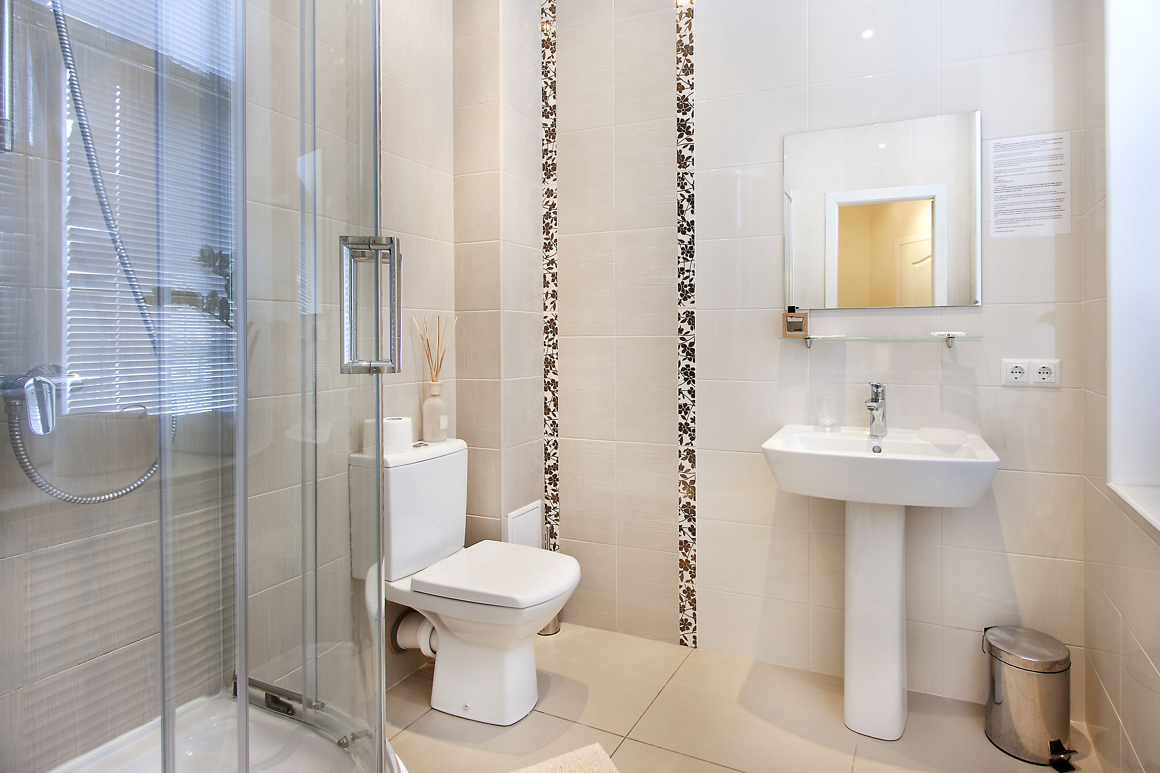 Une salle de bain moderne avec une douche à parois de verre, des toilettes et un lavabo surmonté d’un miroir.