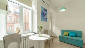 A modern living room with a teal sofa, a white dining table, and a chair. - Centrooms (Kyiv)