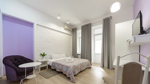 A modern bedroom with a bed, a chair, a small table, and a TV. - Centrooms (Kyiv)