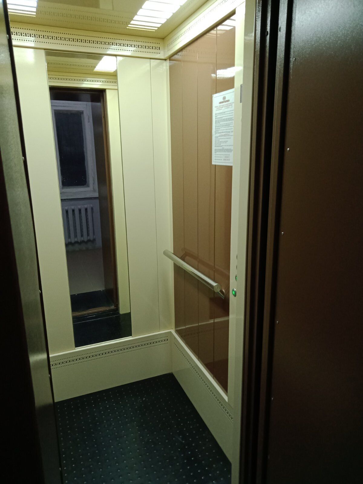 Ein Aufzug mit einem metallenen Geländer und einer Tür mit Lesegerät für Zutrittskarten.