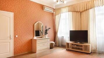 A room with a wooden dresser, a television on a stand, a mirror, and a potted plant.