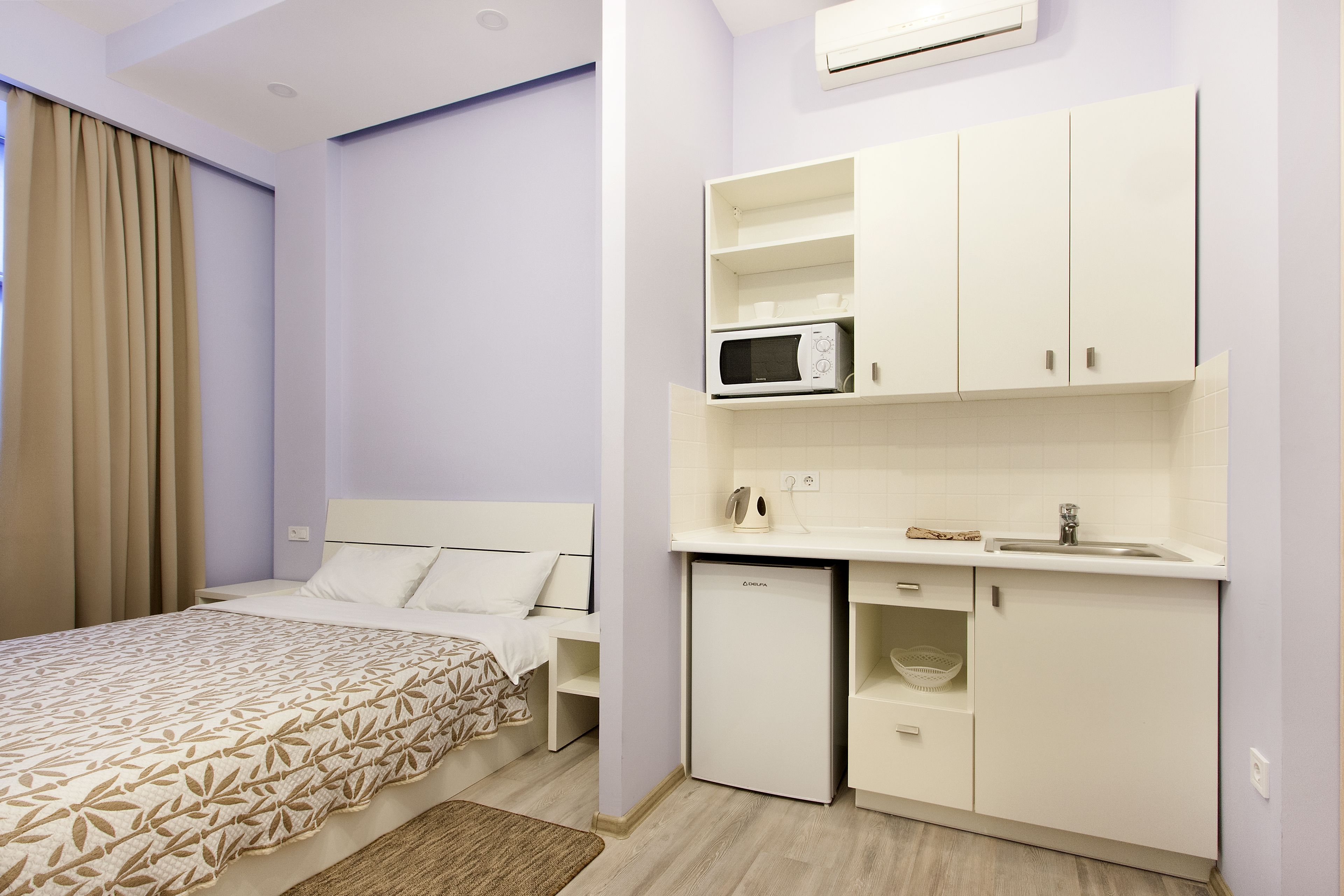 Quarto de hotel compacto com cama, cozinha compacta e pequeno frigorífico.