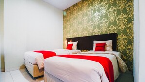 A double bed with red and white bedding, a headboard, and a green patterned wall. - RedDoorz Plus near Mall Panakukang 2 (Makassar)