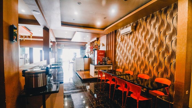 Una cocina moderna con estufa, pileta y comedor con sillas rojas.