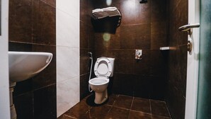 Un baño pequeño con azulejos, que incluye inodoro, lavamanos y ducha.