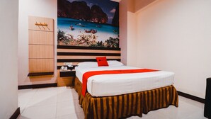 Habitación de hotel con cama, armario de madera y un gran mural de playa en la pared.