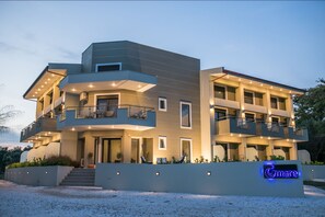 Un immeuble moderne à plusieurs étages, doté de balcons, d’une entrée bien éclairée et d’une enseigne sur laquelle on peut lire « Gmare ».