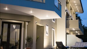 A modern two-story building with a balcony, steps leading to the entrance, and outdoor seating. - Gmare (Polygyros)