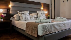 Una habitación de hotel moderna con una cama grande, dos mesitas de noche y una lámpara de pared.