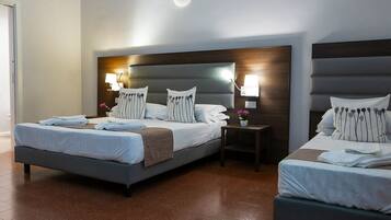 Une chambre d’hôtel avec deux lits, une table de chevet et une lampe fixée au mur.