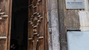 Una puerta de madera con un diseño geométrico, un letrero que dice "RE VITTORIO DE LUXE ACCOMMODATIONS" y una pared de piedra.