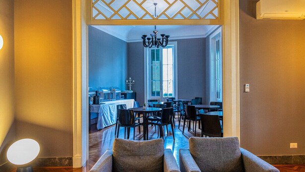 Un vestíbulo de hotel con mostrador de recepción, zona de estar y vista al comedor.
