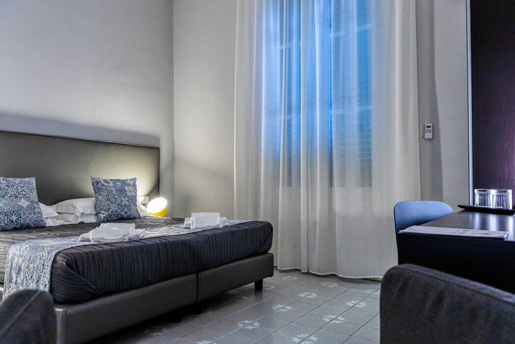 A hotel room with a bed, a desk, and a chair.