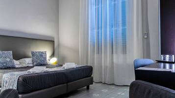 A hotel room with a bed, a desk, and a chair.