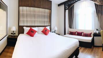 A hotel room with a large bed, a seating area, a TV, and a bathroom with a glass shower.