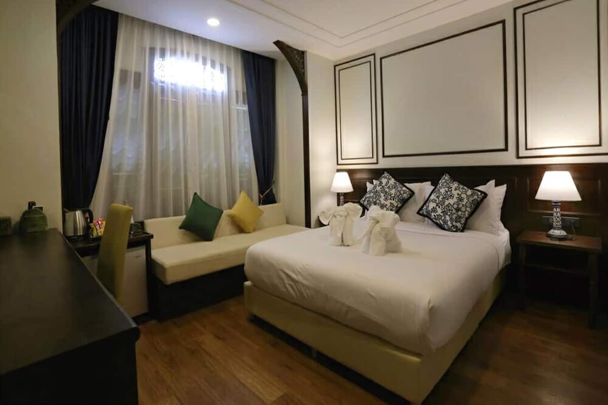 A hotel room with a bed, a sofa, a desk, and a nightstand.