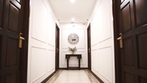A hallway with dark wooden doors, white walls, and a decorative mirror on the wall. - Elliebum Boutique Hotel (Chiang Mai)