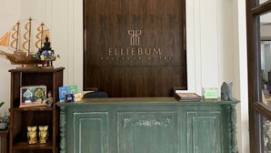 A reception desk with a wooden backdrop and the name 'Elliebum Boutique Hotel' displayed. - Elliebum Boutique Hotel (Chiang Mai)