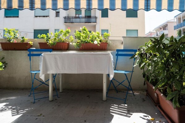 A small outdoor patio with a table and two blue chairs, surrounded by potted plants. - Ca' Rebeka Venice (Mestre)
