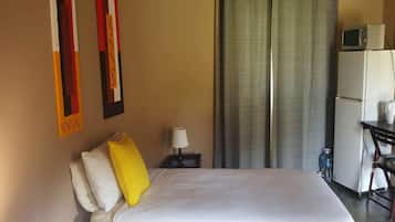 Una habitación de hotel con cama, escritorio, computadora, microondas y refrigerador.