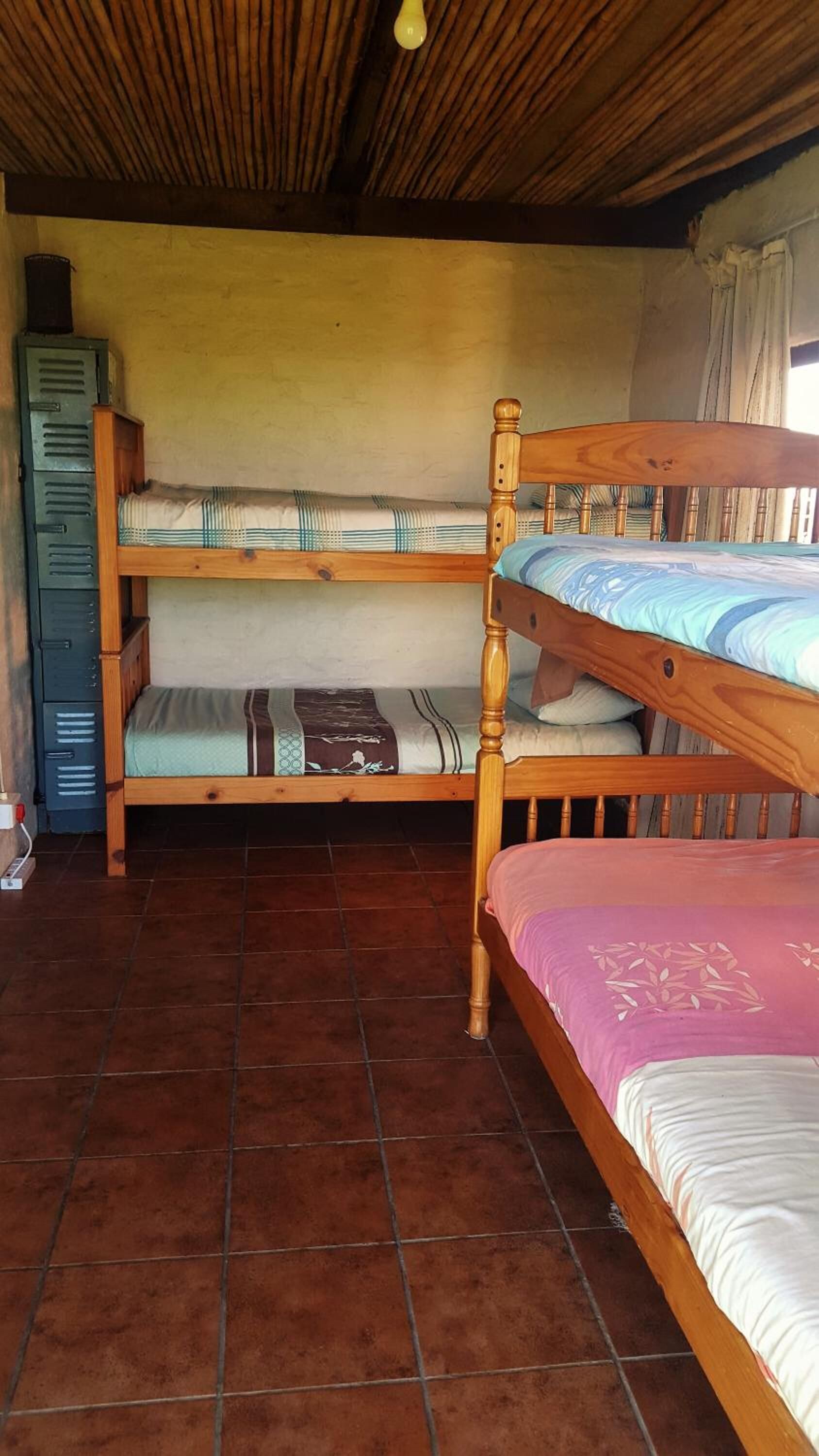 A room with two wooden bunk beds, a tiled floor, and a wooden ceiling.