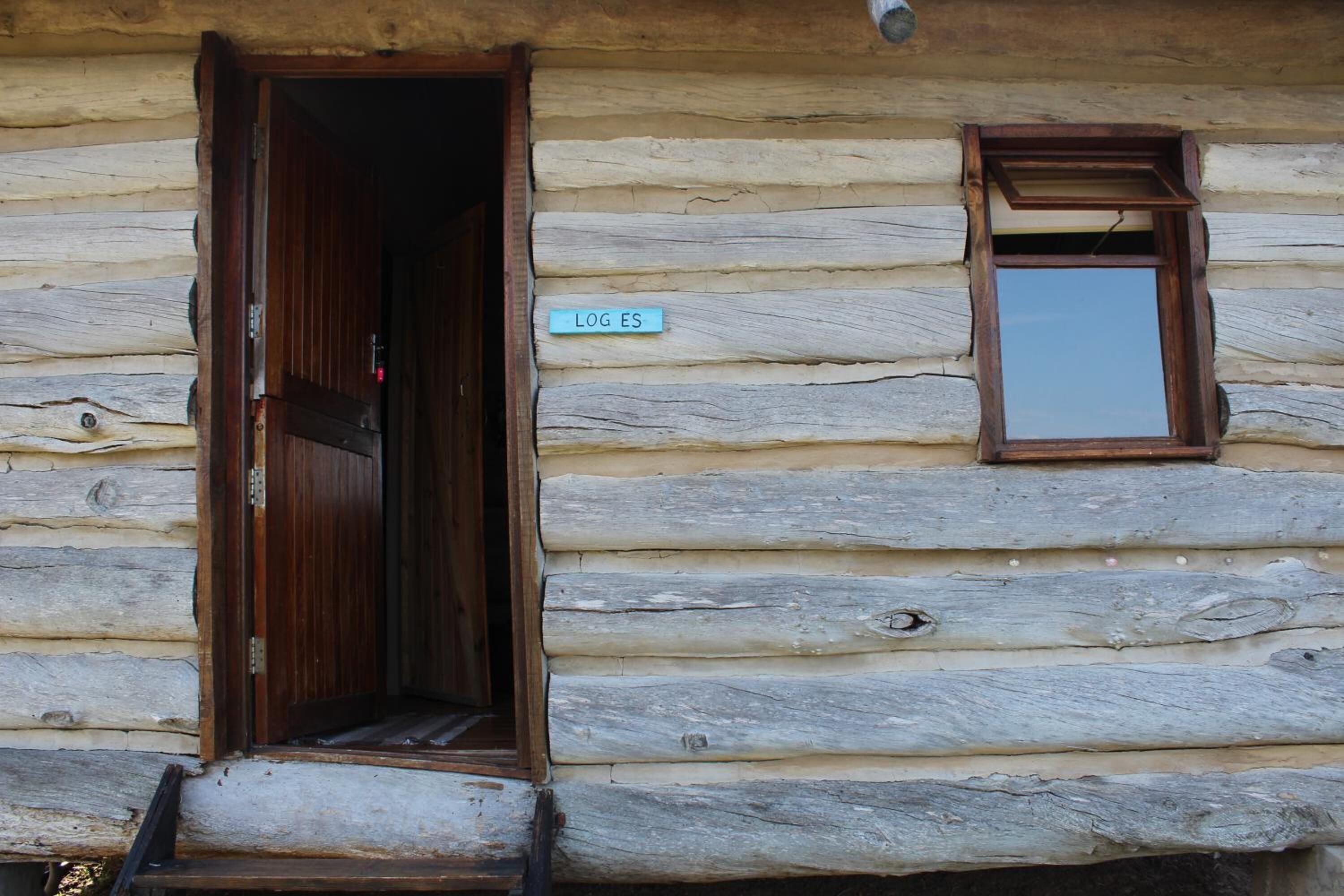 A log cabin with a wooden door and a small window.
