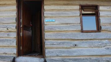 A log cabin with a wooden door and a small window.