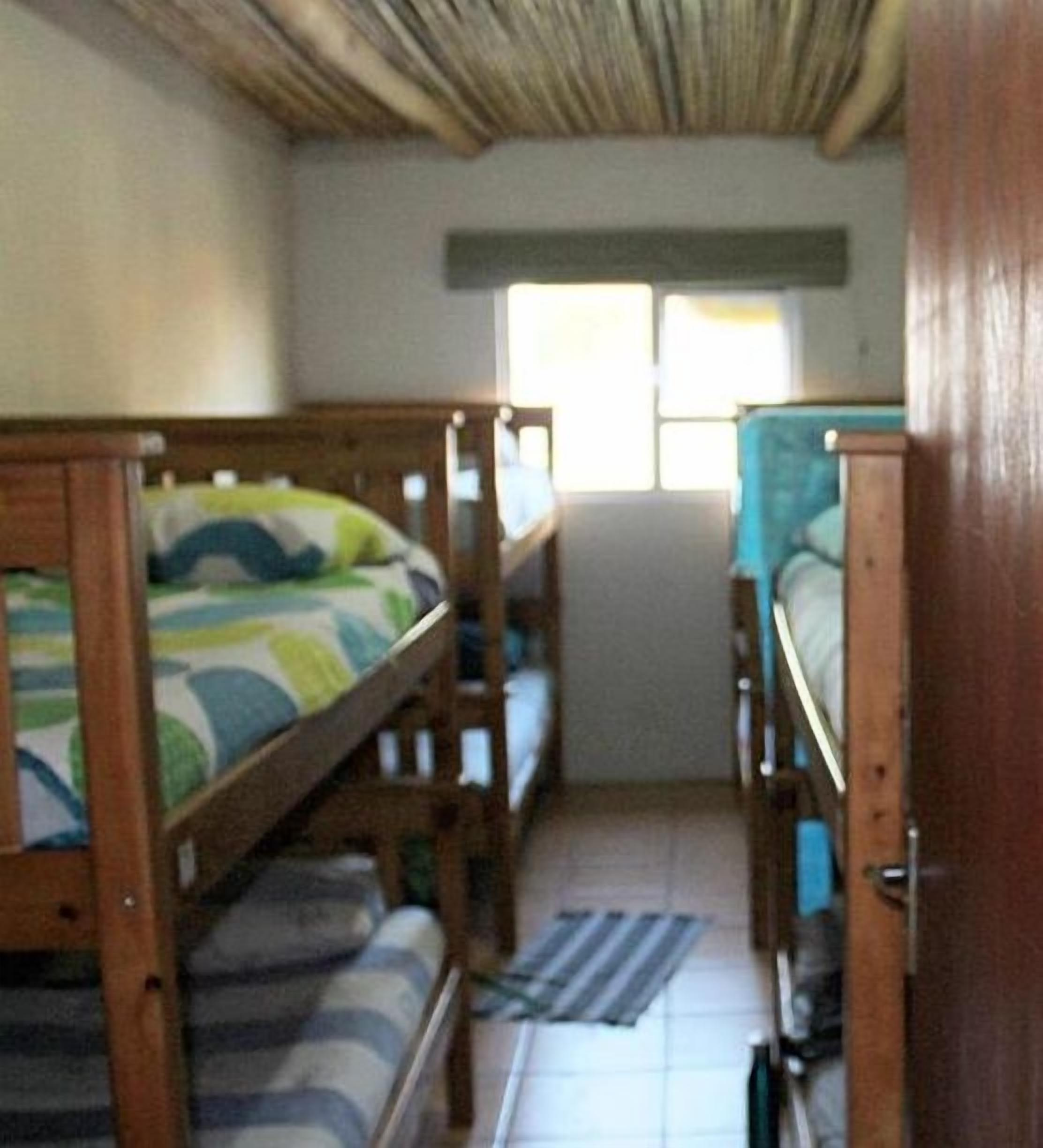 A room with bunk beds, a window, and a door.