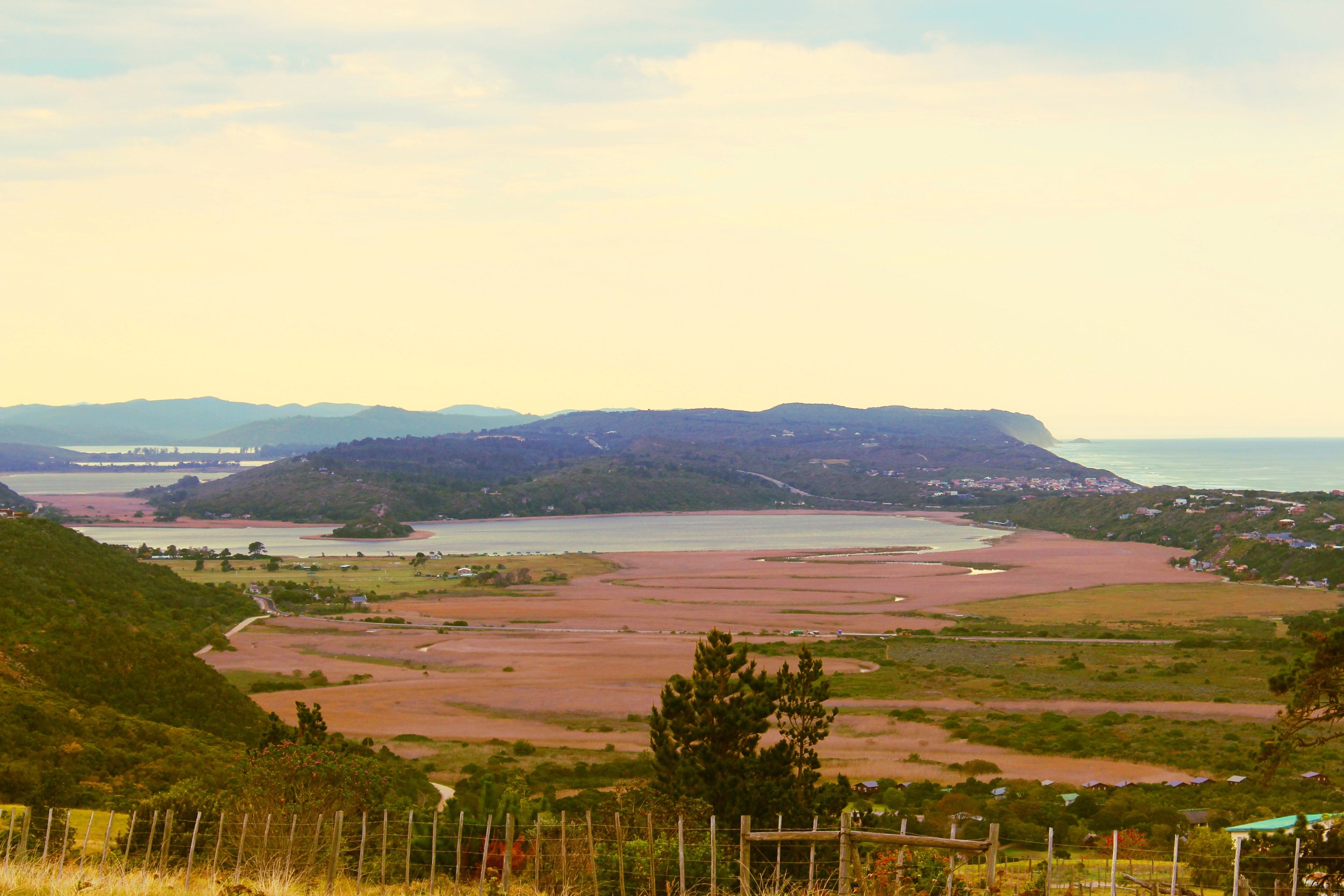 Un paysage côtier offrant une vue sur la mer, des collines et un petit village.