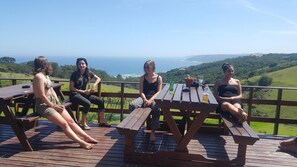 A group of people sitting at a wooden picnic table with a scenic ocean view in the background.