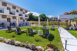 A courtyard with outdoor seating, a pool, and a building with balconies. - Rooms 48 by Zante Plaza (Zakynthos)