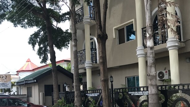 A multi-story building with a beige facade, white columns, and balconies with black railings. - GQ International Hotel (Abuja)
