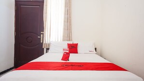 Ein Hotelzimmer mit einem Bett, einer roten Tagesdecke und einer Tür.