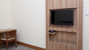 A room with a built-in TV on a wooden cabinet, a small table with two glasses, and a chair.