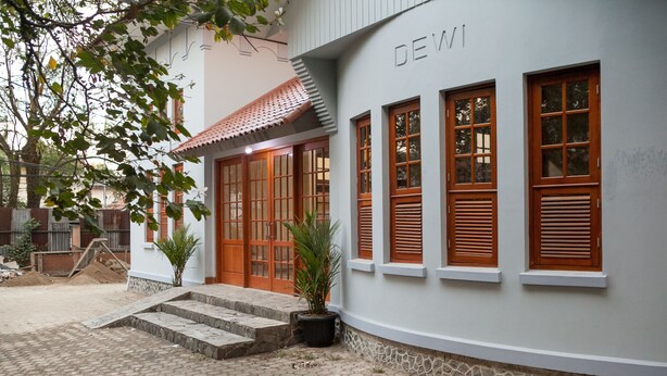 A building with a white exterior, wooden shutters, and a nameplate reading "DEWI".
