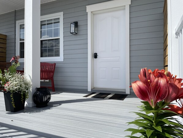 A house with a white door, a red bench, and potted plants on the porch.
