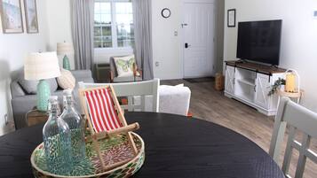 A living room with a round black table, a television, and a sofa.