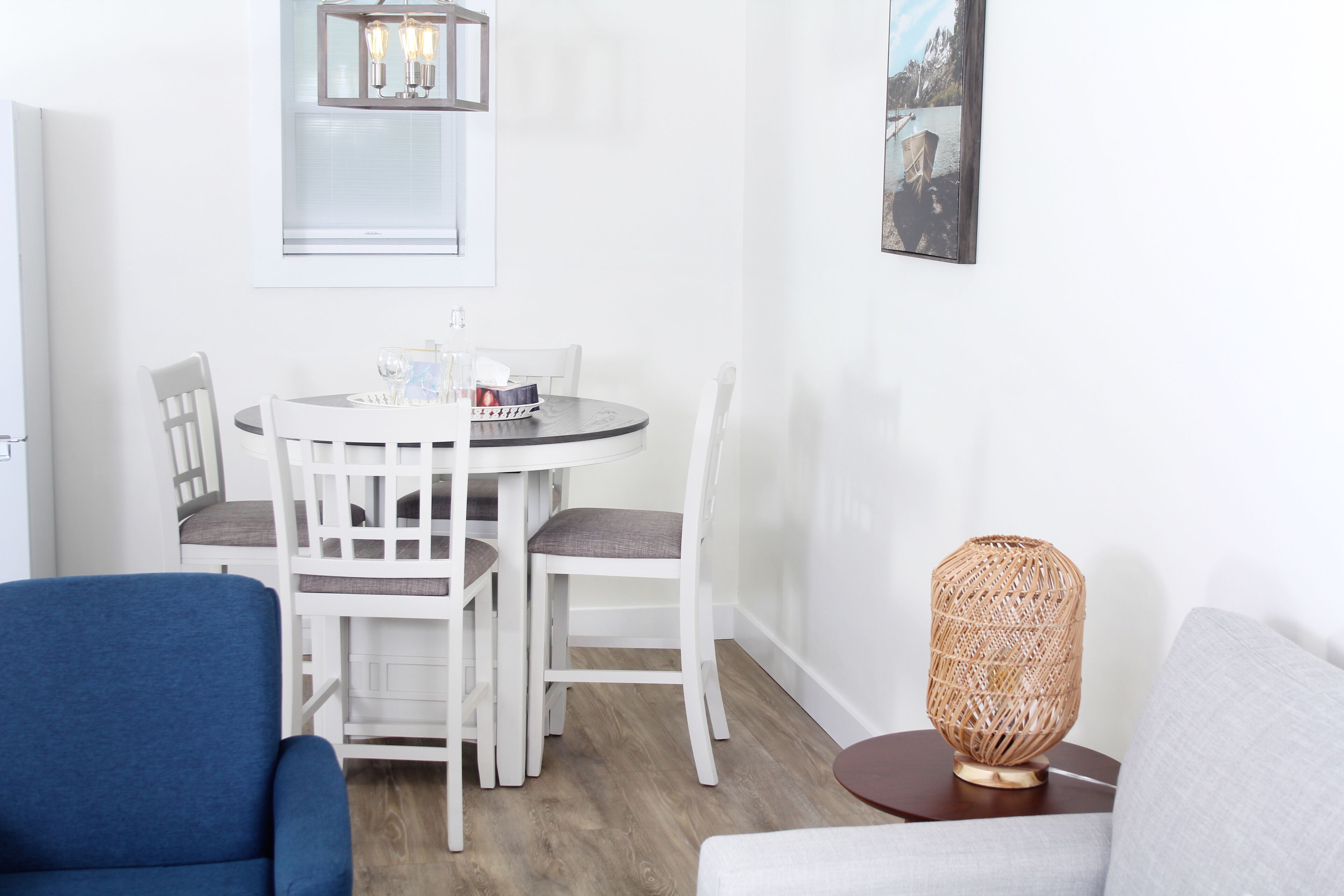 Un coin repas avec une table ronde, des chaises blanches et un fauteuil bleu.