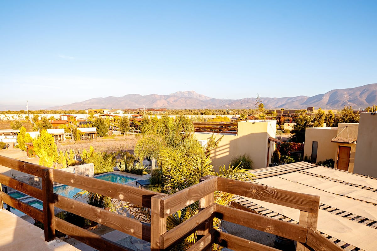 A rooftop with a pool, wooden deck, and views of mountains.