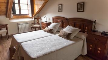 Un dormitorio con dos camas, muebles de madera, un escritorio y una ventana con cortinas.