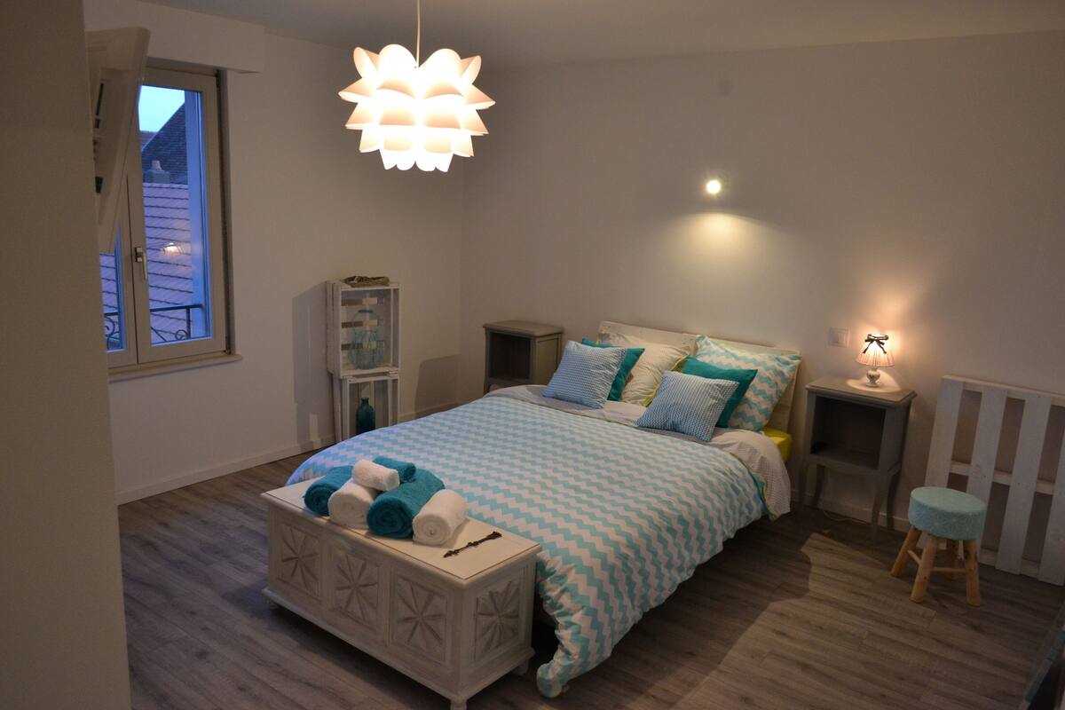 Ein Schlafzimmer mit einem Bett, Nachttischen, einer Lampe, einem Fenster und einer Heizung.