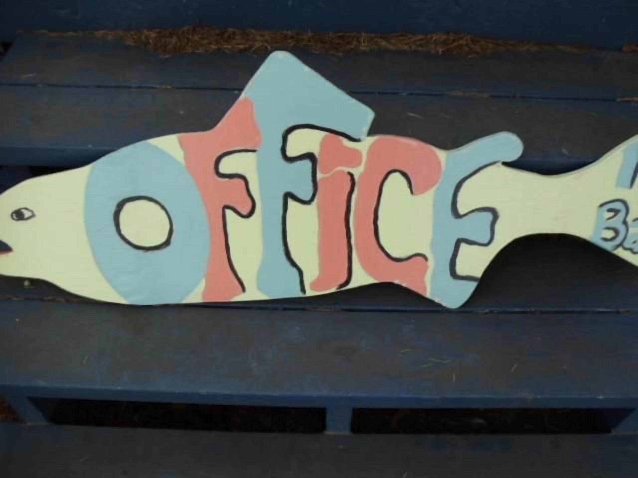 A wooden fish-shaped sign with the word 'OFFICE' painted on it.