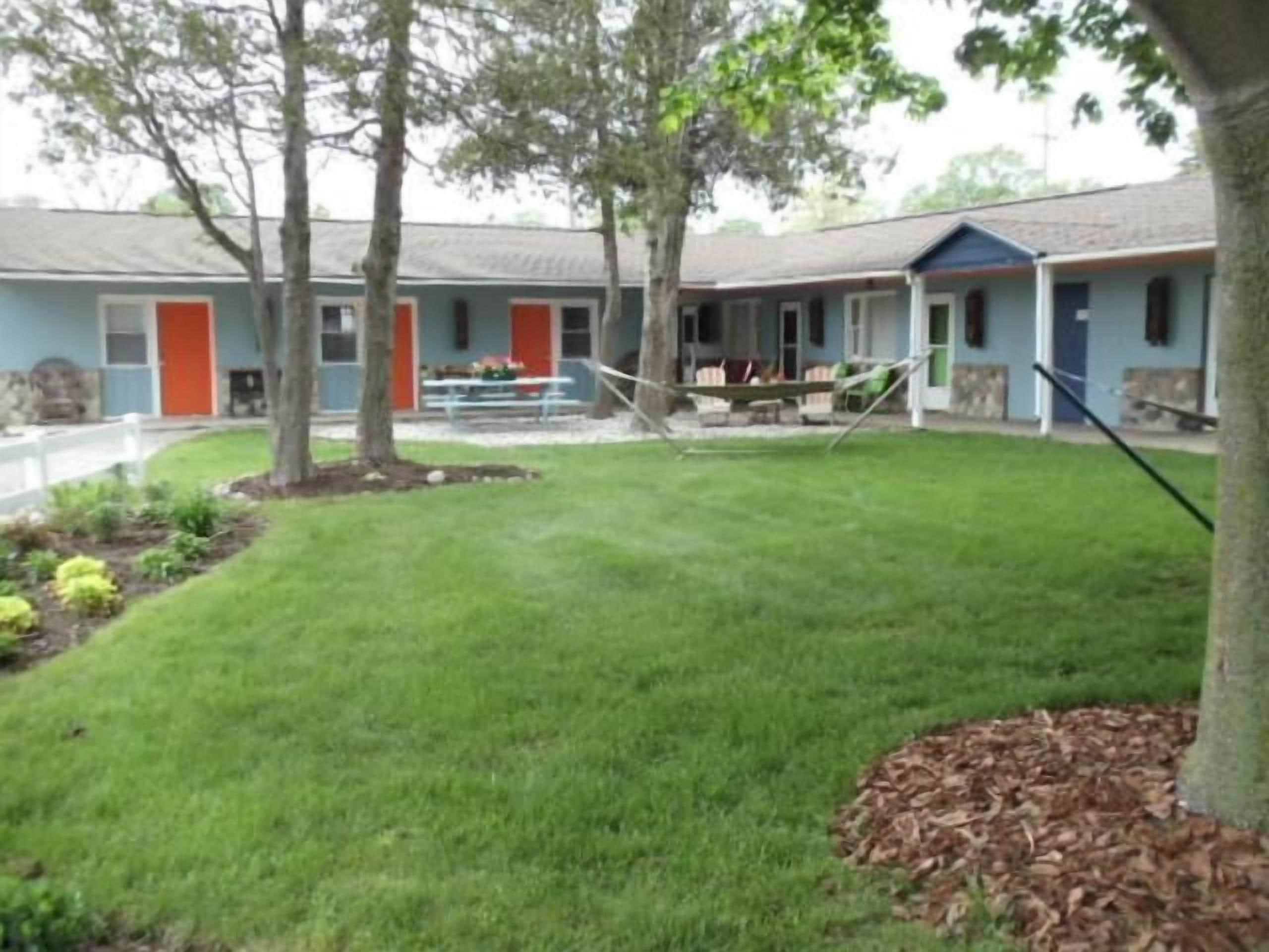 A property with a well-maintained lawn, a hammock, and a building with a porch.