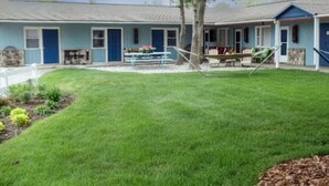 A two-story building with a blue exterior, a front porch with a swing, and a well-maintained lawn. - Bay Port Lodging (Frankfort)