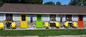 A row of motel rooms with numbered doors, outdoor seating, and flower boxes. - Bay Port Lodging (Frankfort)